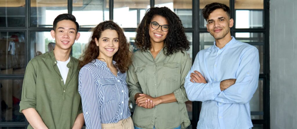 Happy smiling colleagues young creative team students standing looking at camera in modern office. 